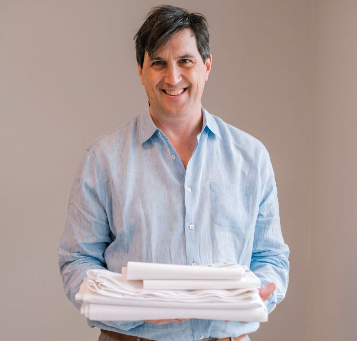 Owner of Charleston Prestige holding a stack of cleaned linens